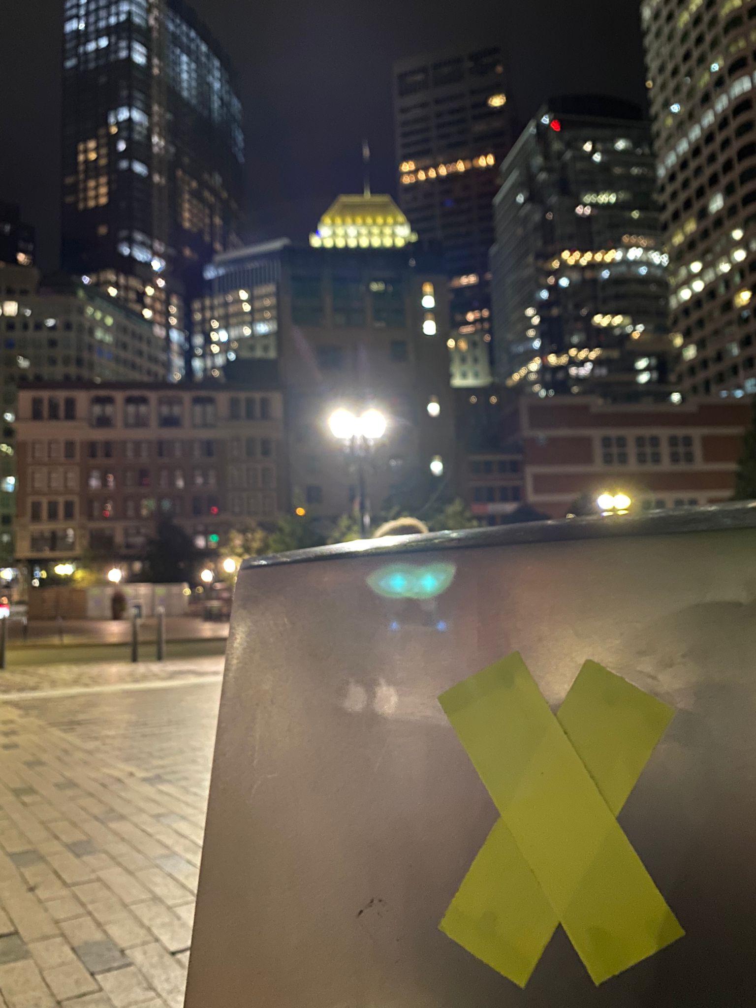 Gele absumo op een muurtje, met op de achtergrond het verlichte South Station in Boston